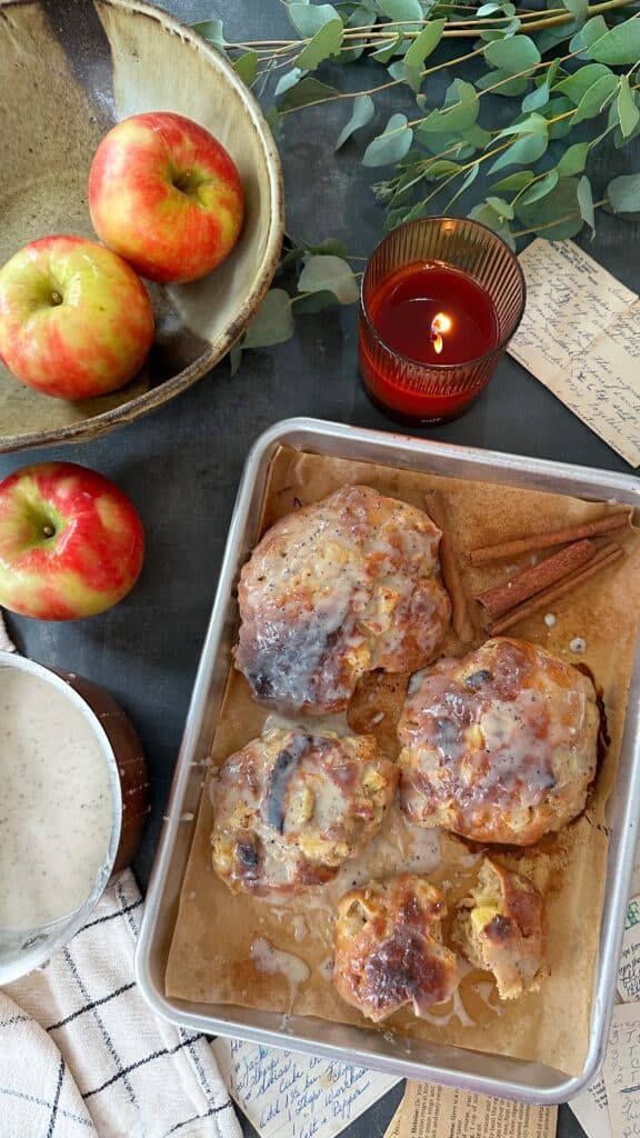 Freshly baked apple fritters with cinnamon on a baking sheet.