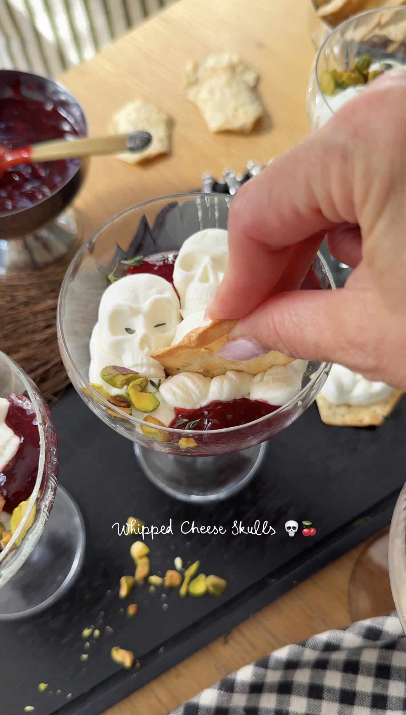 Decorative whipped cheese skulls in a glass bowl for fall appetizer.