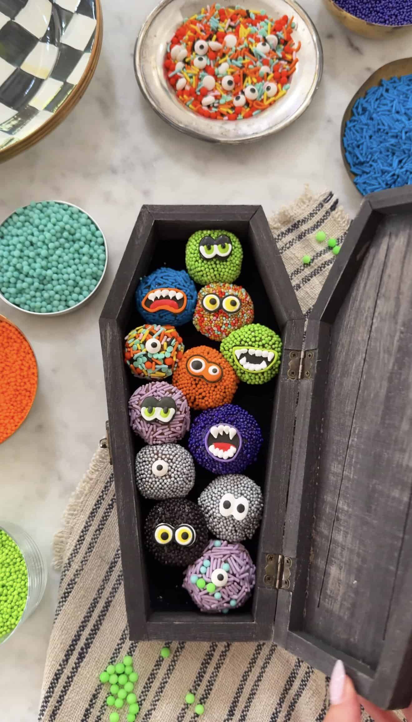 Colorful monster-themed brigadeiro candies in a black box for Halloween.