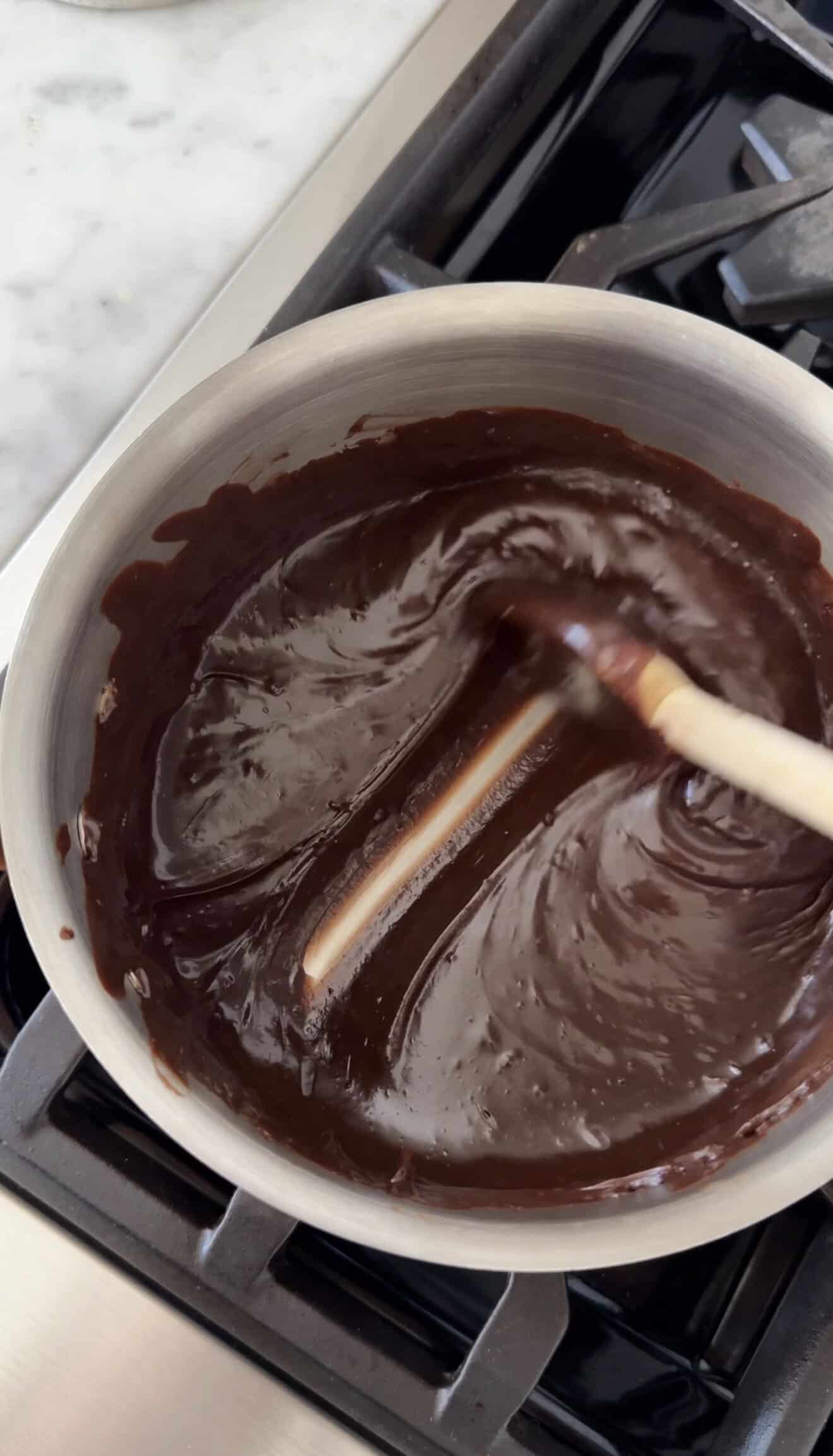 Creamy chocolate ganache being stirred in a bowl for Halloween desserts.
