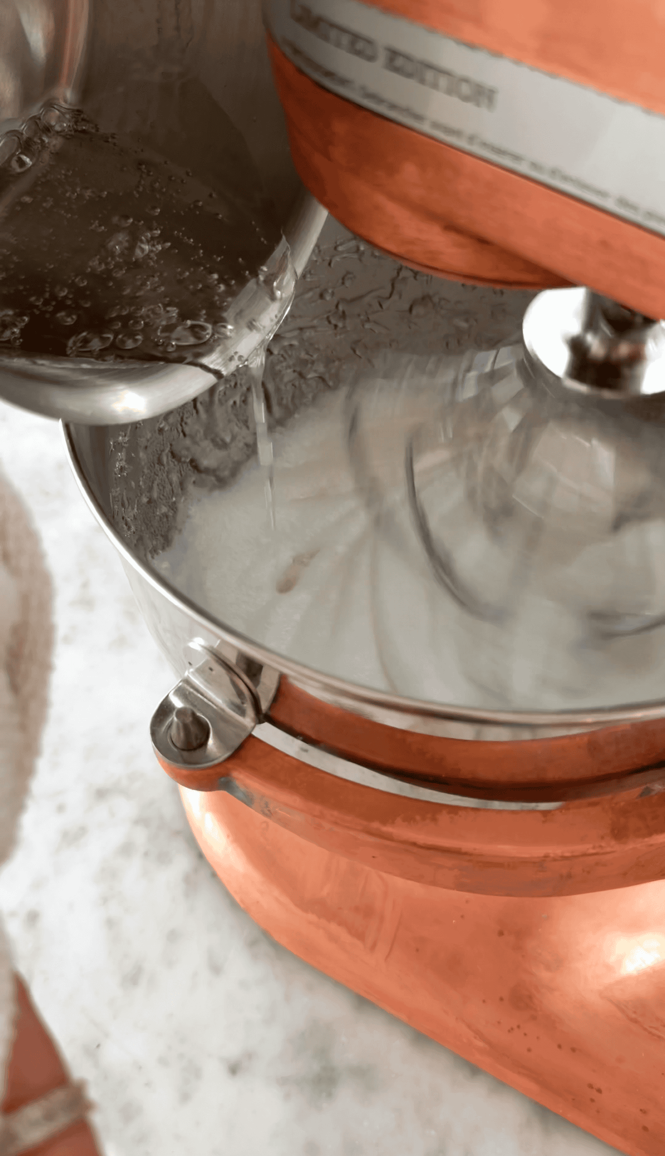 Close-up of a mixer blending cocoa and marshmallow fluff in a copper mixer.