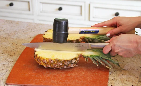 Now you need to halve the halves. One pineapple gives you 4 boats so we are basically quartering the pineapple. Do exactly as Papa taught you above. Line up your knife in the middle of the pineapple halve and hit it with your mallet.